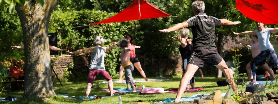 Menschen beim Qoutdoor-Yoga auf einer Wiese