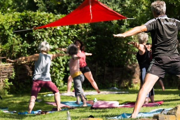 Menschen beim Qoutdoor-Yoga auf einer Wiese
