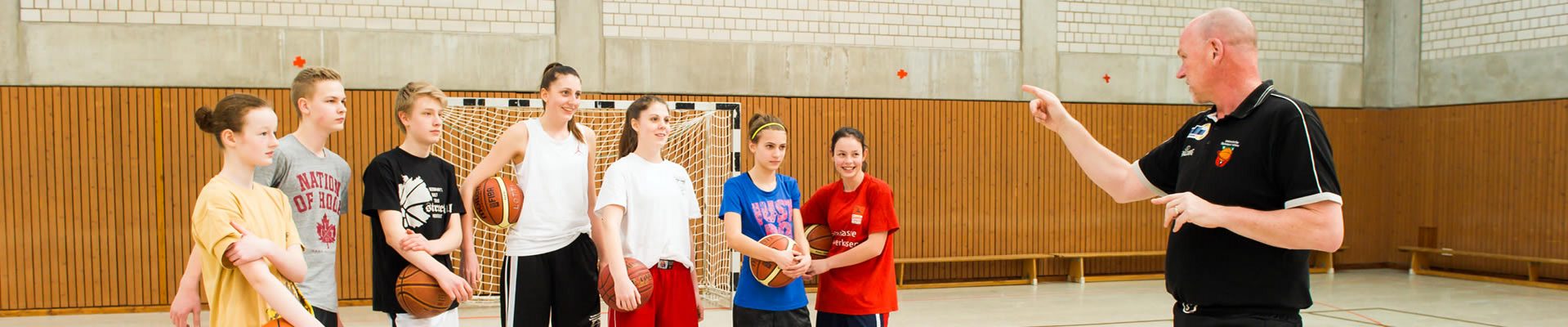 Jugendliche Ballspielgruppe mit Trainer in der Sporthalle