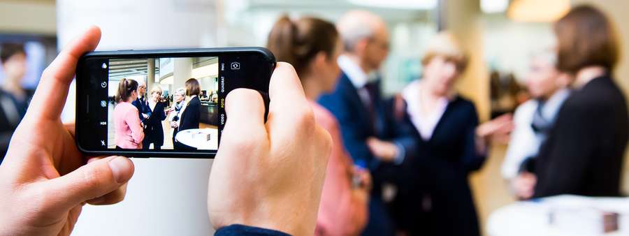 Mann fotografiert Menschen mit Smartphone