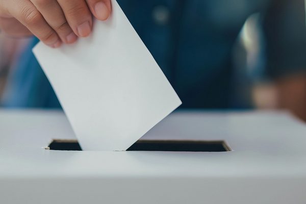 Hand wirft Wahlzetter in Wahlurne