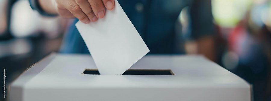 Hand wirft Wahlzetter in Wahlurne