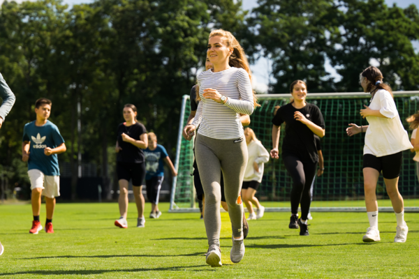 Jugendliche auf einer Wiese treiben Sport im Rahmen eines Sprachcamps