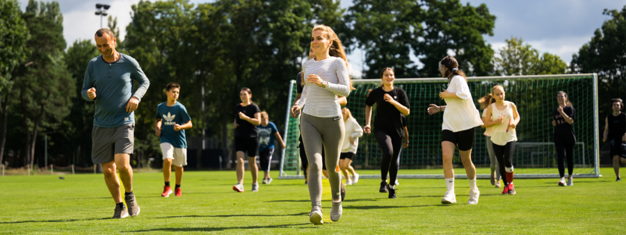 Jugendliche auf einer Wiese treiben Sport im Rahmen eines Sprachcamps