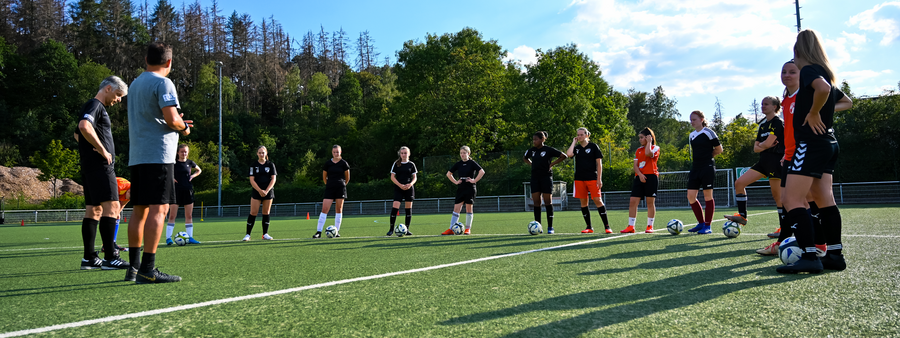Symbolbild: Teambesprechung mit den Trainern auf dem Sportplatz