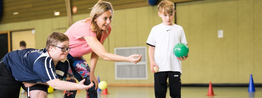 Übungsleiterin und 2 Jungen in der Turnhalle beim Sport