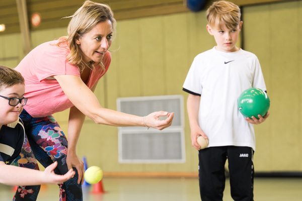 Übungsleiterin und 2 Jungen in der Turnhalle beim Sport