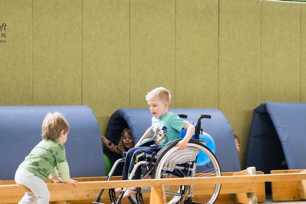 Übungsleiterin in Sporthalle mit Kindern mit und ohne Behinderung (Symbolbild für soziale Verantwortung)
