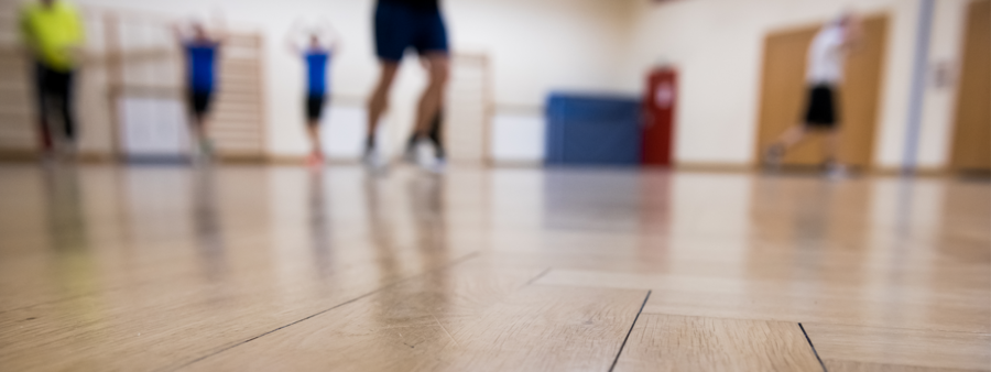 Symbolbild: Sporthalle mit Menschen - Bild zu Unkenntlichkeit verschwommen
