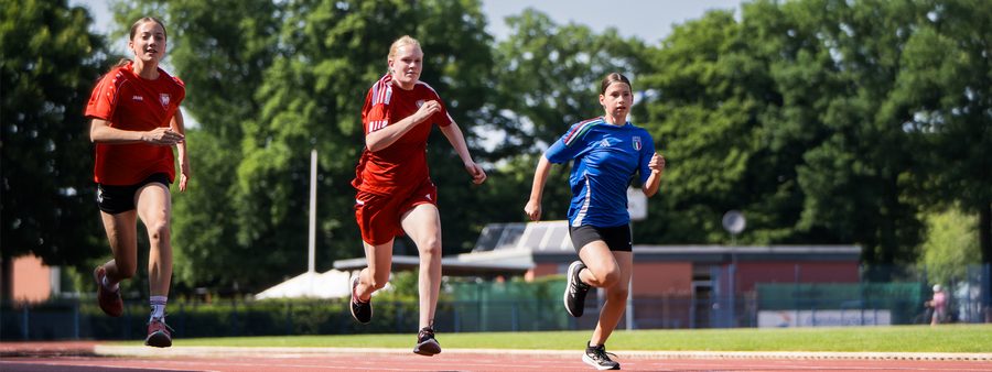 3 Mädchen laufen draußen auf Tartanbahn