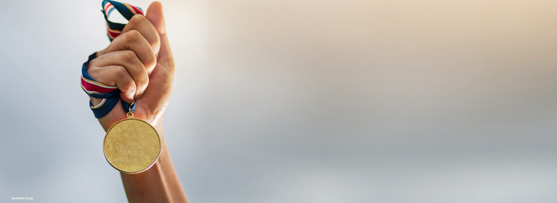 Hand hällt Medaille in die Luft (Symbolbild)