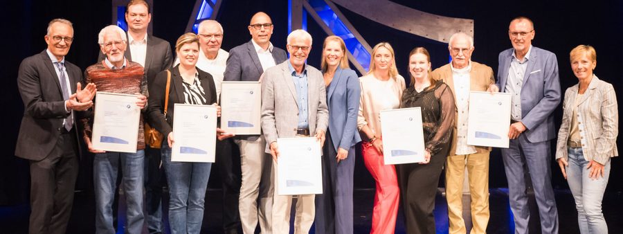Gewinner auf der Bühne halten Urkunden in der Hand