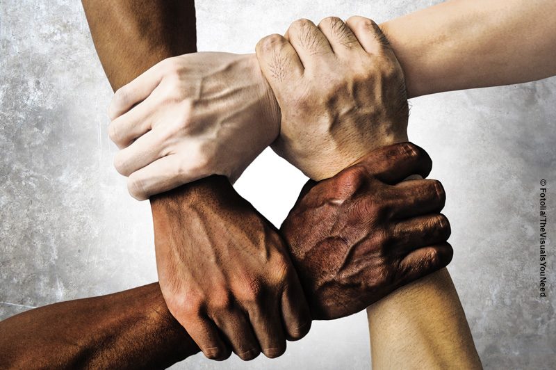 4 Hände unterschiedlicher Hautfarben halten sich fest (© AdobeStock_TheVisualsYouNeed)