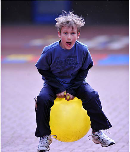 Bild: Ein Kind springt auf einem Hüpfball und schneidet eine Grimasse.