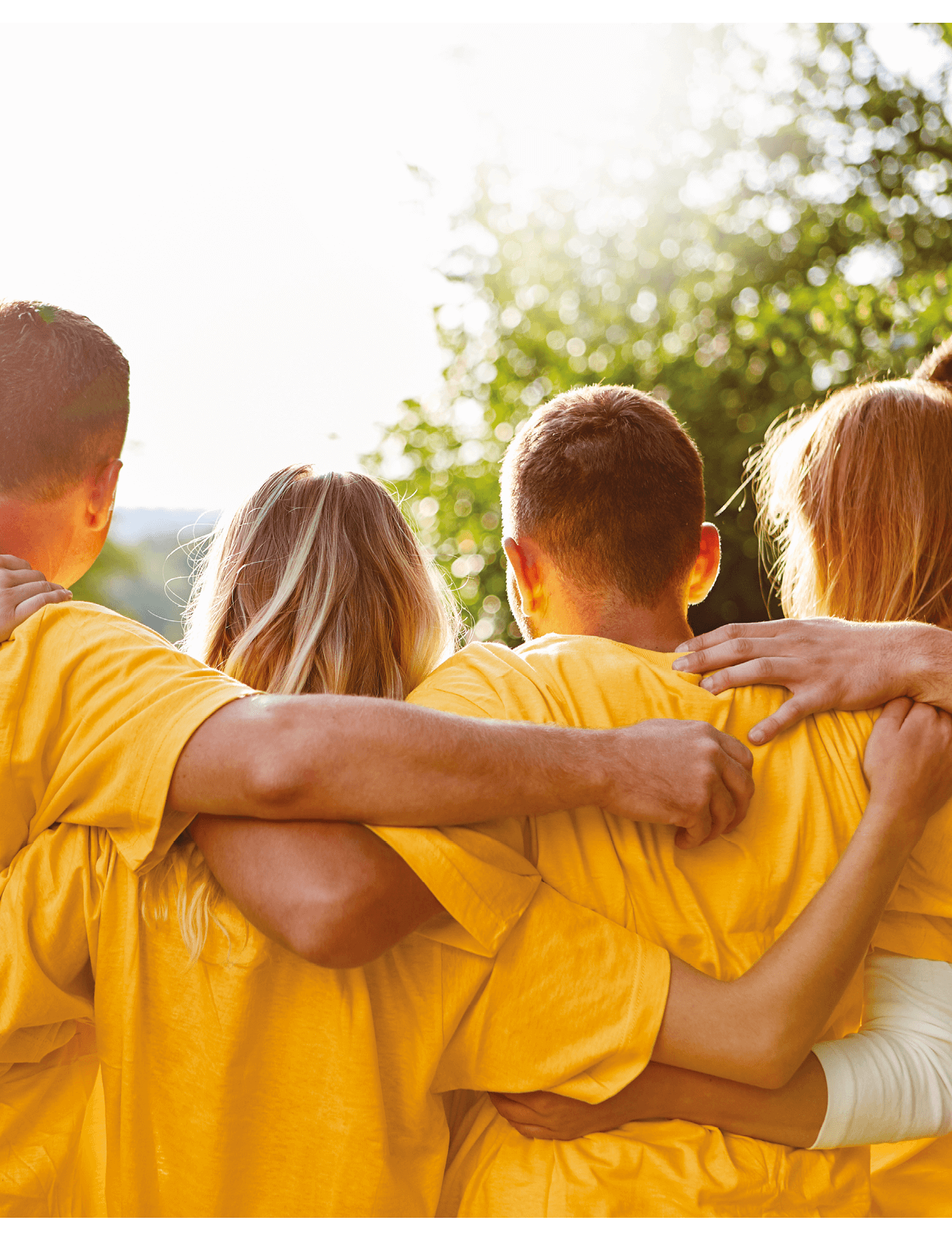 Junges starkes Team umarmt sich bei einem Teambuilding Event in der Natur