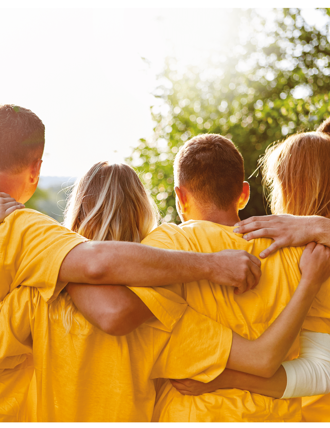 Junges starkes Team umarmt sich bei einem Teambuilding Event in der Natur